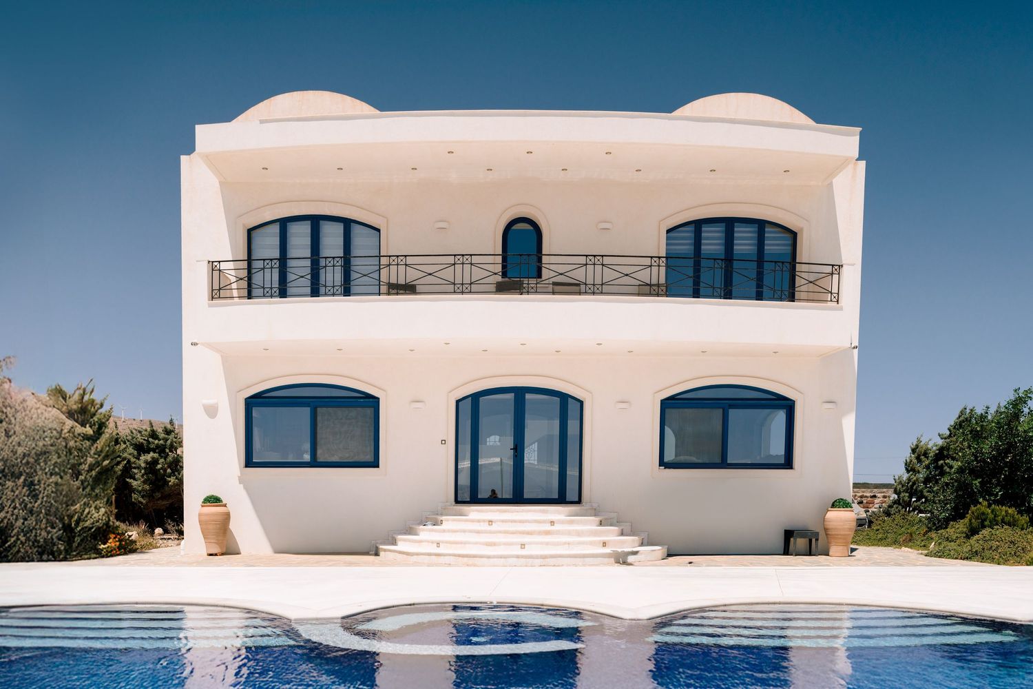 Modern white Mediterranean villa with arched windows and swimming pool.
