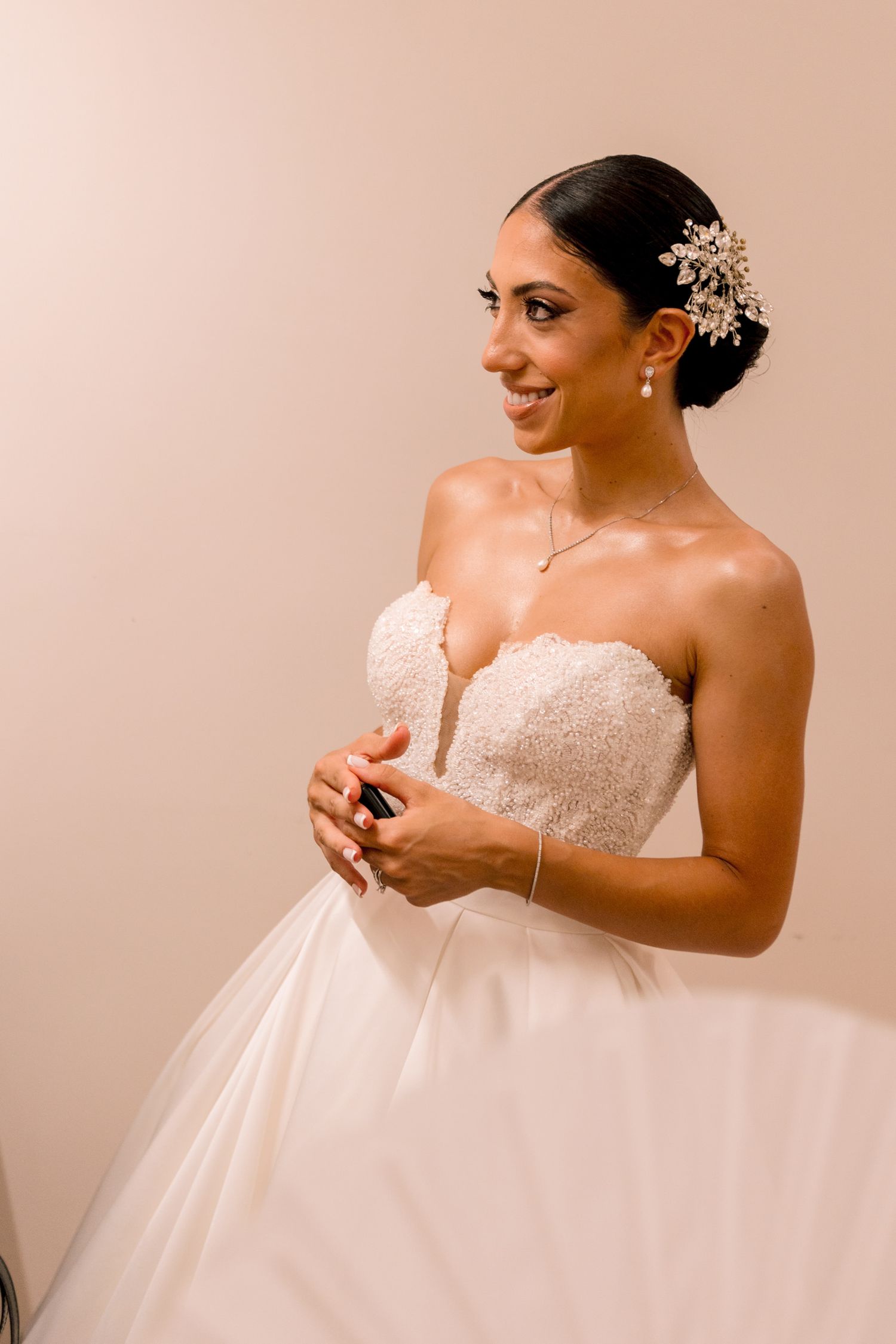 Elegant bride in strapless lace wedding gown during final preparations.