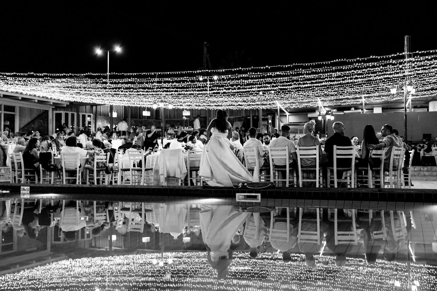 An outdoor wedding reception venue with white string lights illuminating the space.