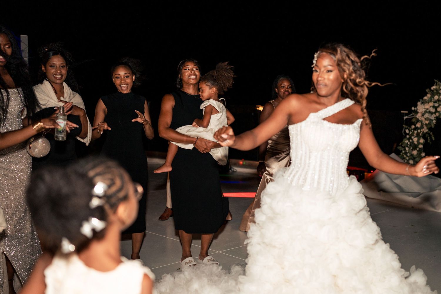 A bride dances energetically with wedding guests during the reception celebration.