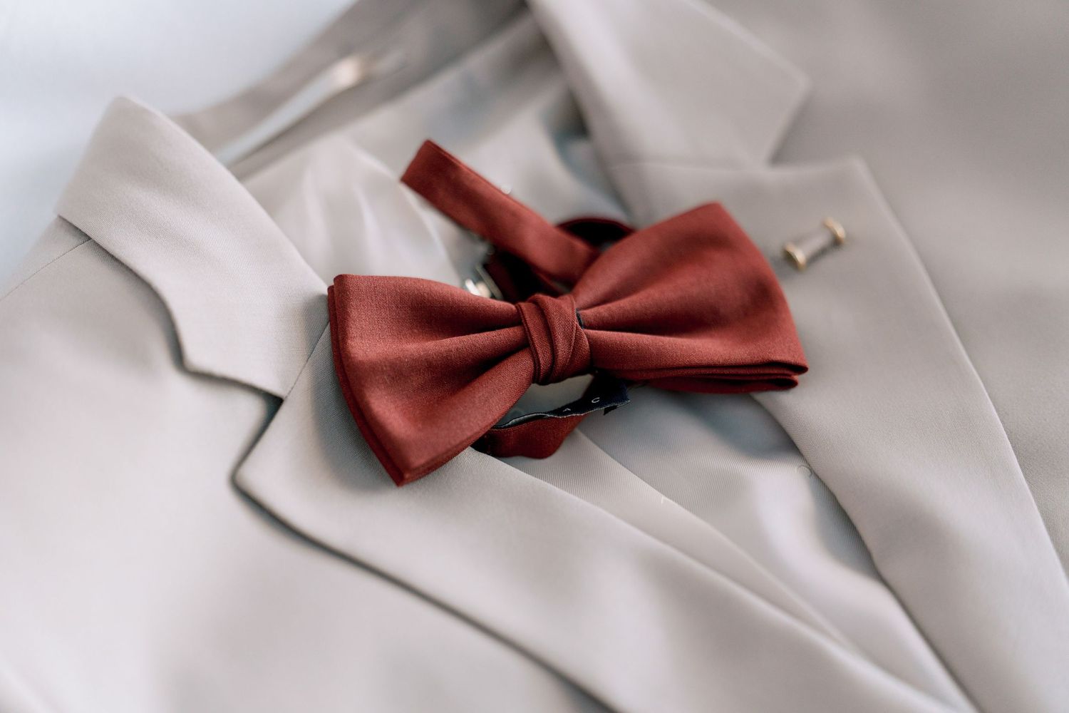 Red bow tie and white formal wear accessories laid out on light surface.