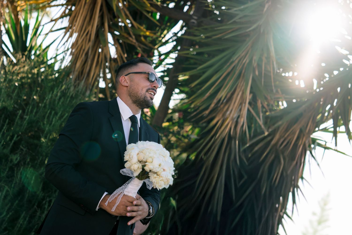 Wedding couple walking through palm trees in golden sunlight.
