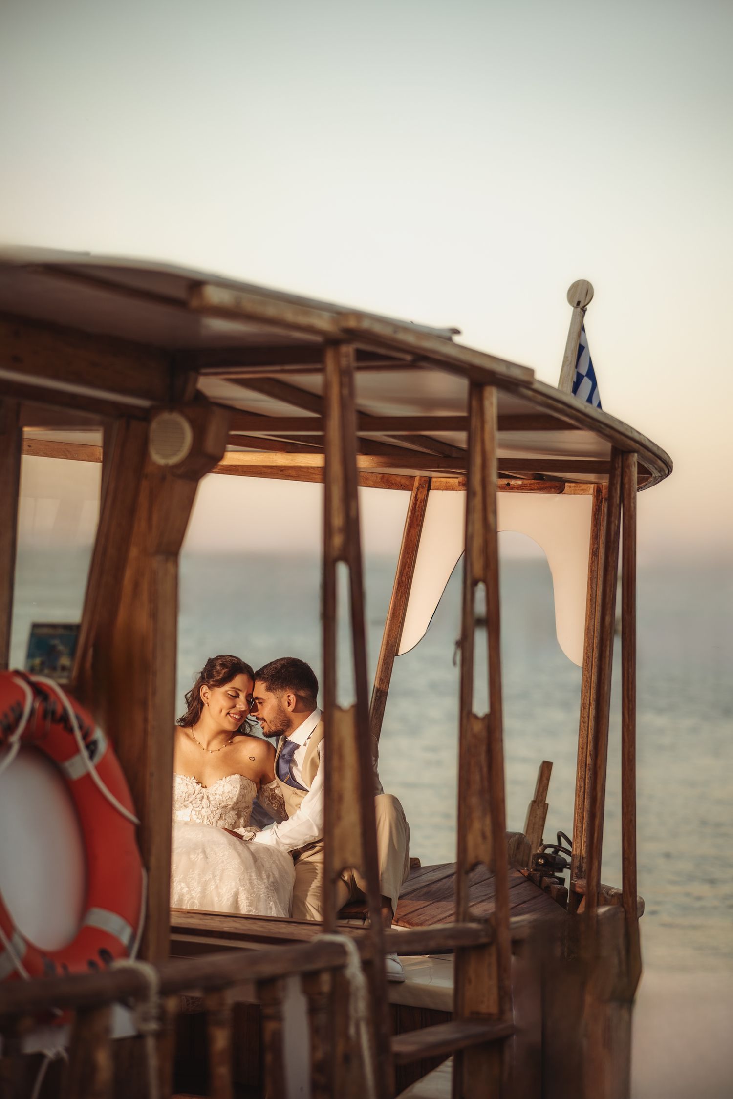 Wedding couple sharing intimate moments aboard a vintage wooden boat at sea.