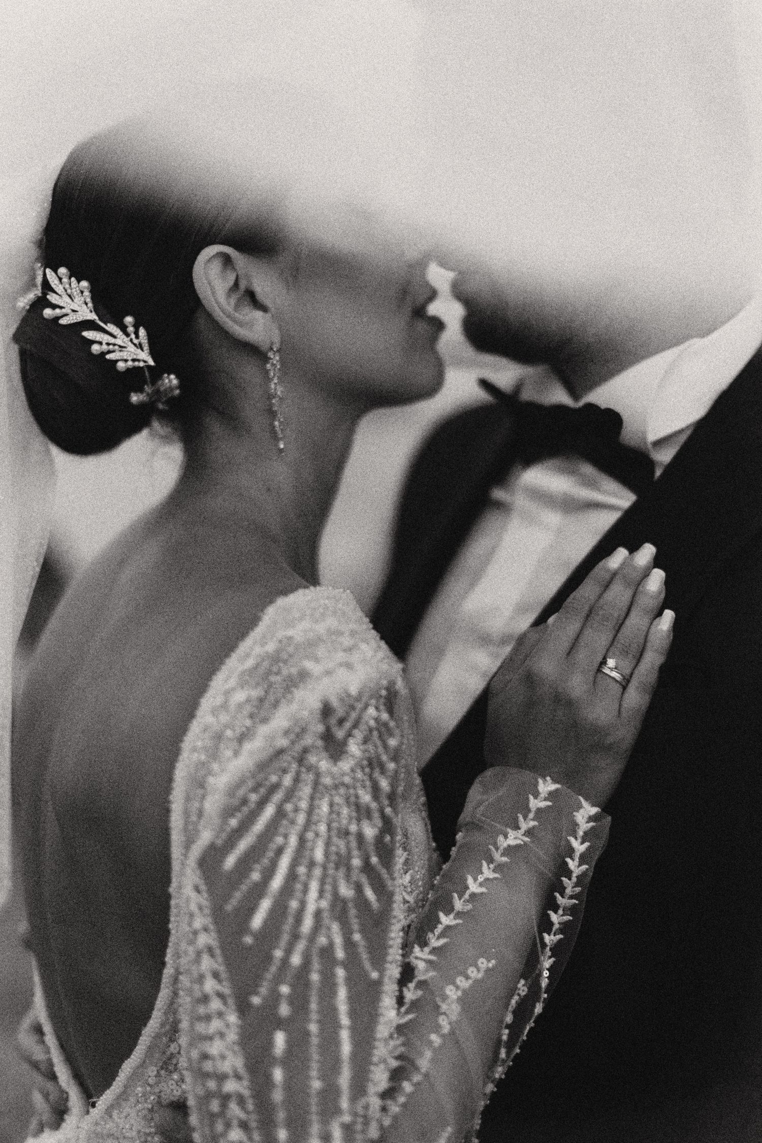 Artistic black and white wedding portrait showing bride's detailed beaded gown and jewelry.