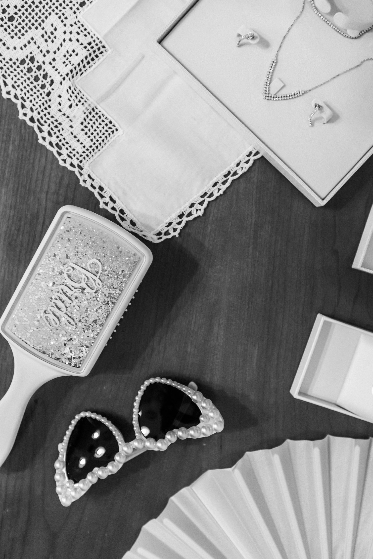 Wedding accessories including lace details and jewelry arranged on dark surface.