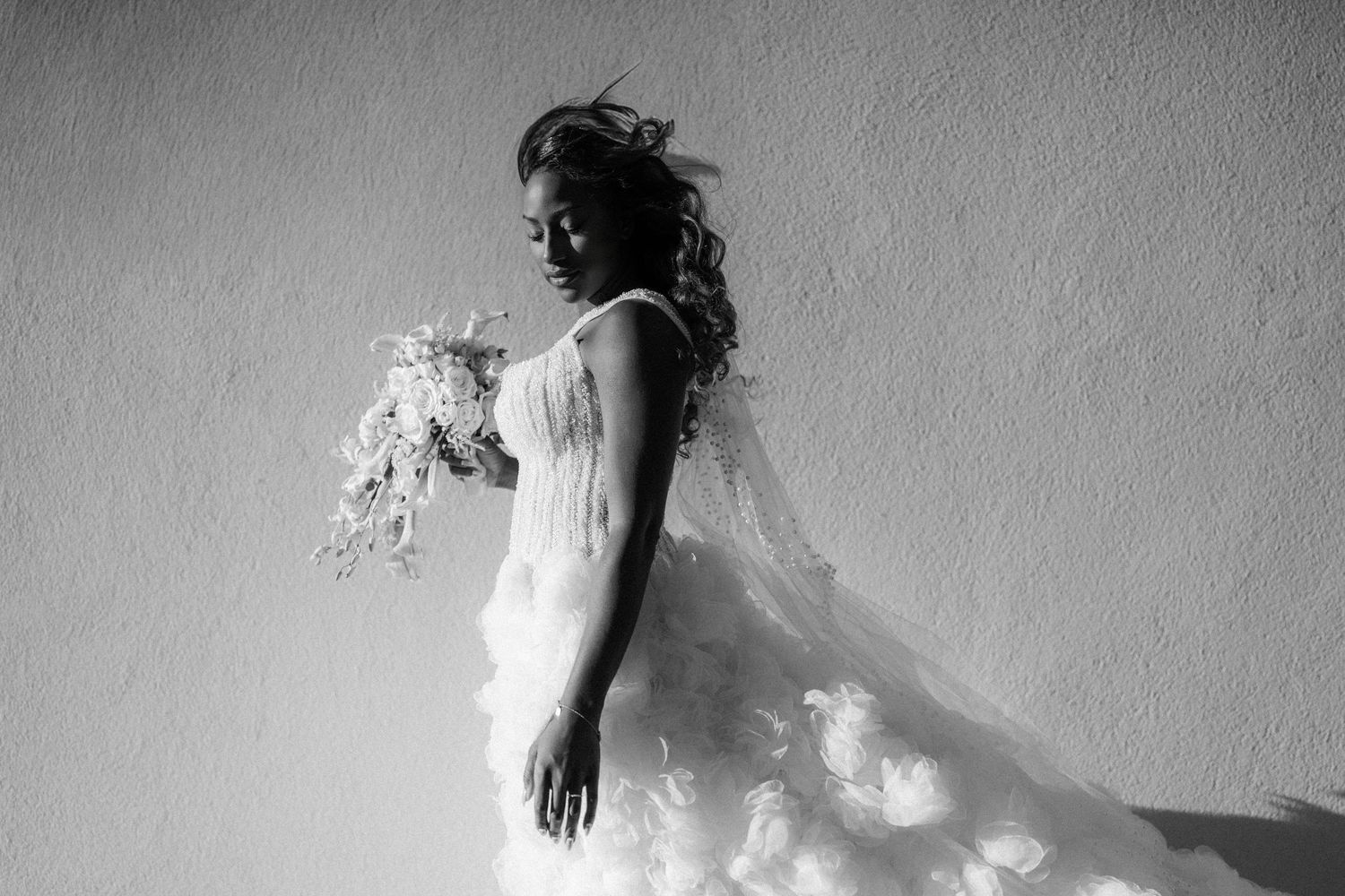 Elegant bridal silhouette in black and white against a light wall.