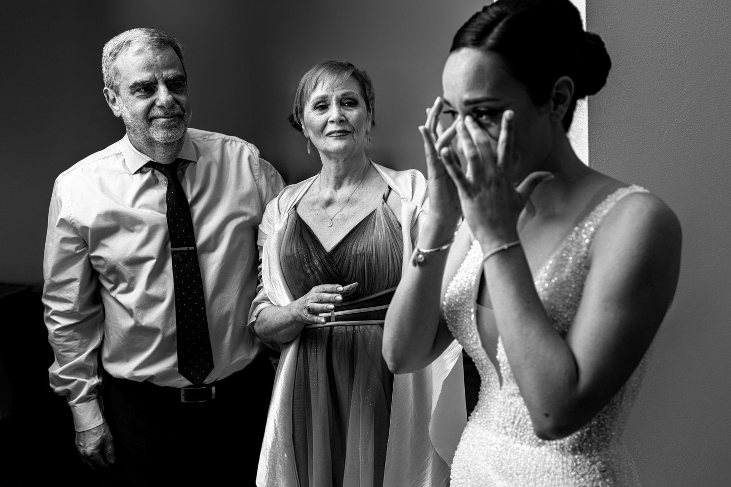 Emotional candid black and white wedding moment captured indoors.