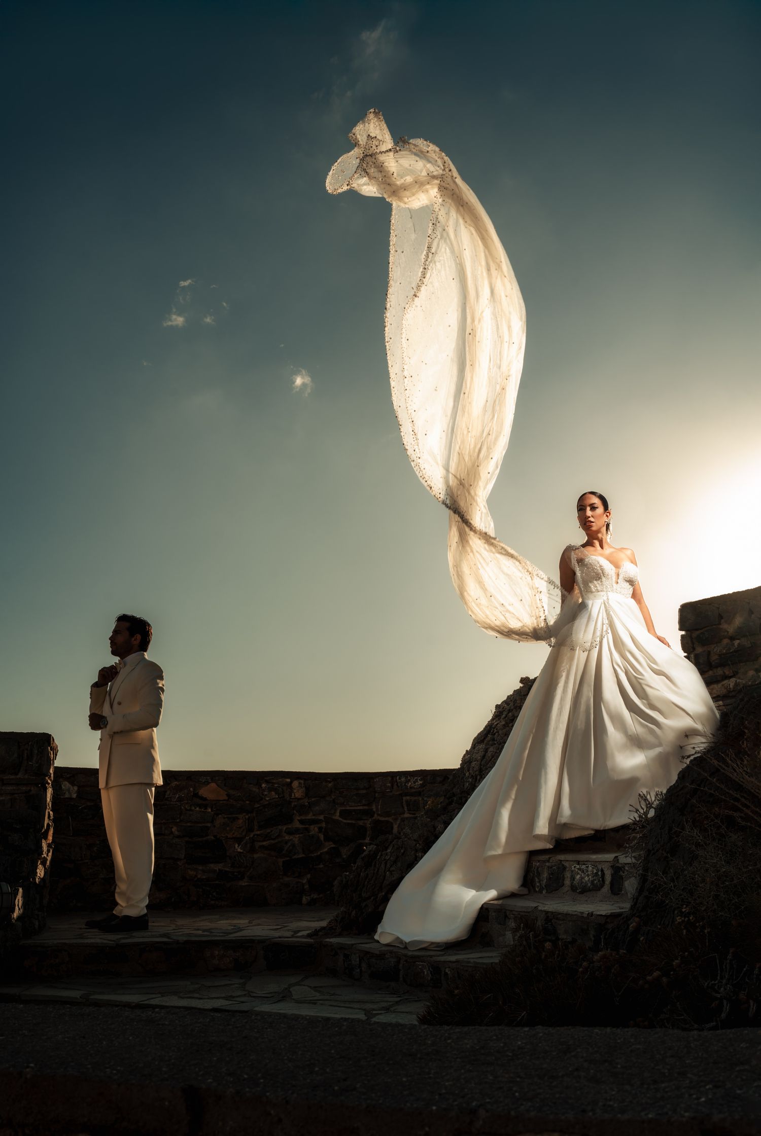 White wedding dress billowing in wind against dramatic sky.