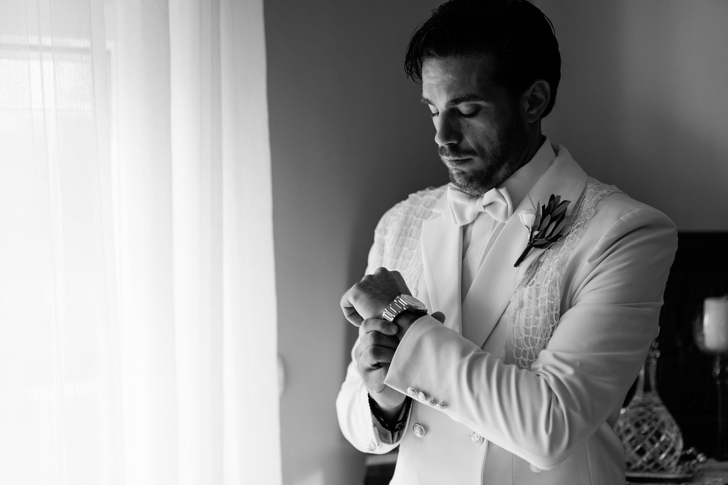 Side profile of groom in white suit making final adjustments before the ceremony.