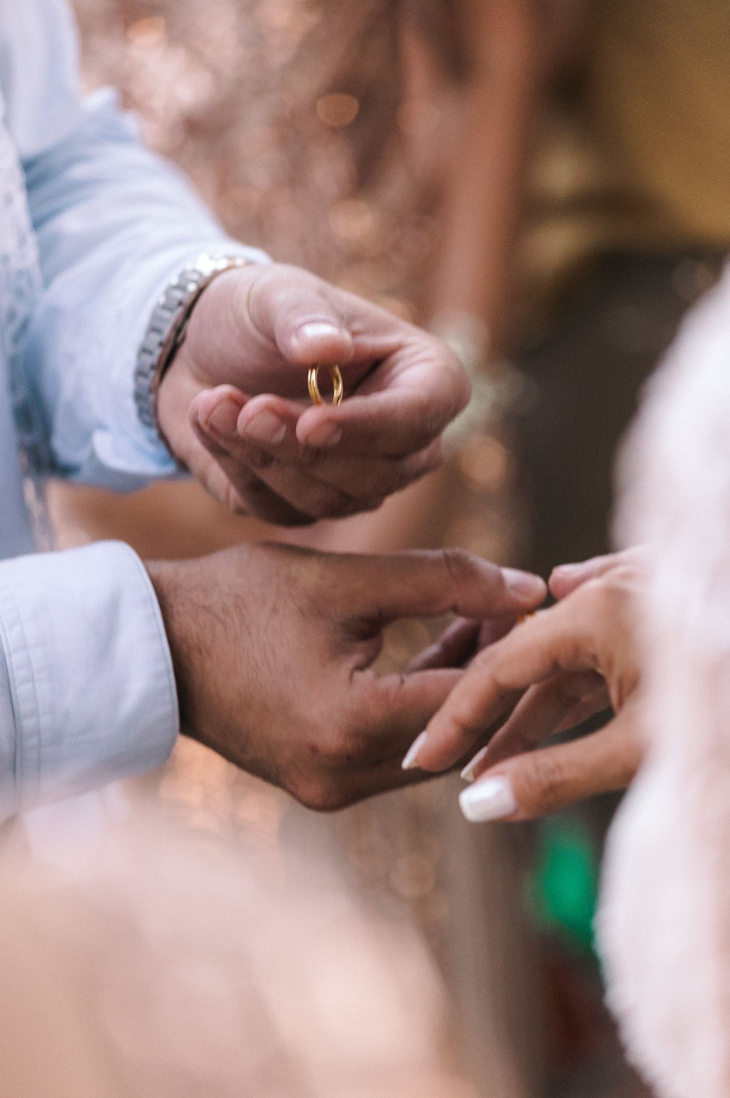 Close-up of hands exchanging wedding rings during ceremony.