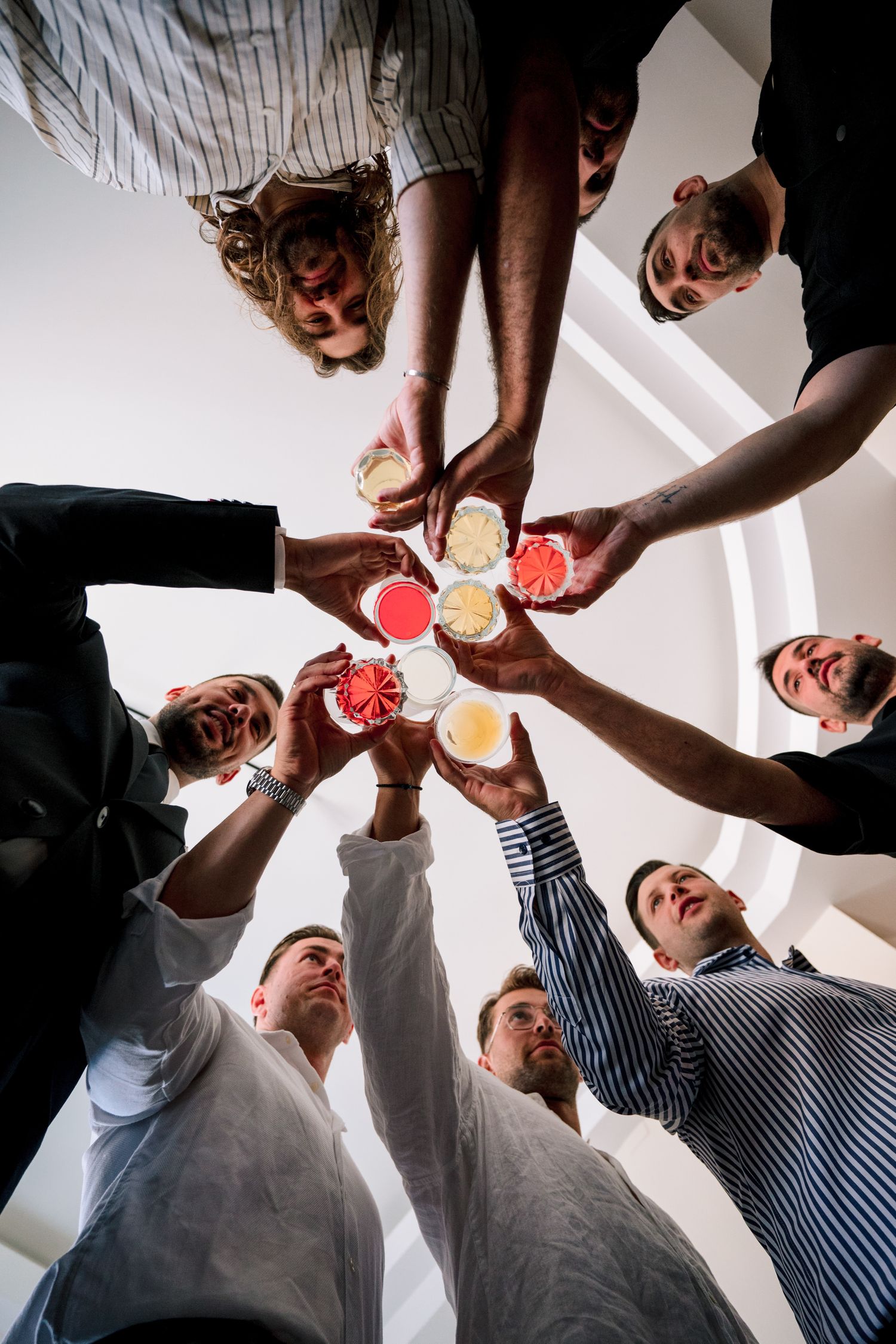 Low angle view of group toasting with drinks in a circle formation.