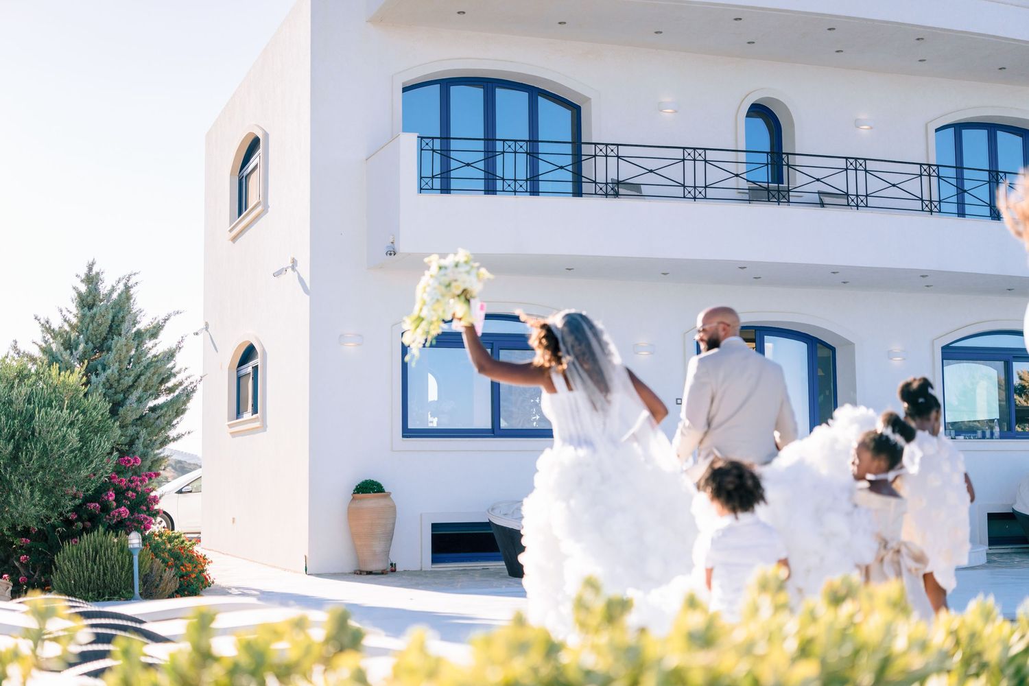 Mediterranean-style white building with blue accents and arched windows against clear sky.