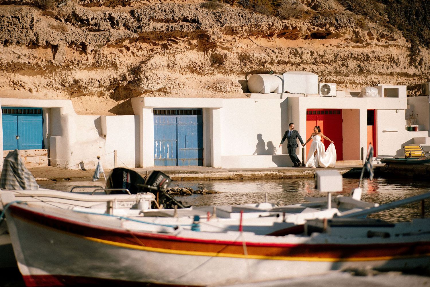 Mediterranean harbor scene with traditional fishing boats and whitewashed buildings.