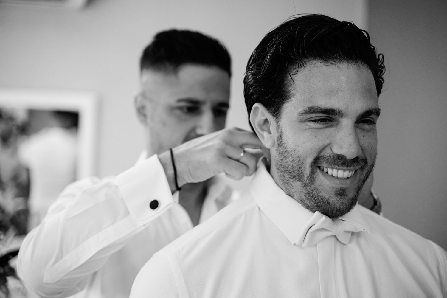 Black and white photo of groomsmen sharing joyful moments during wedding preparations.