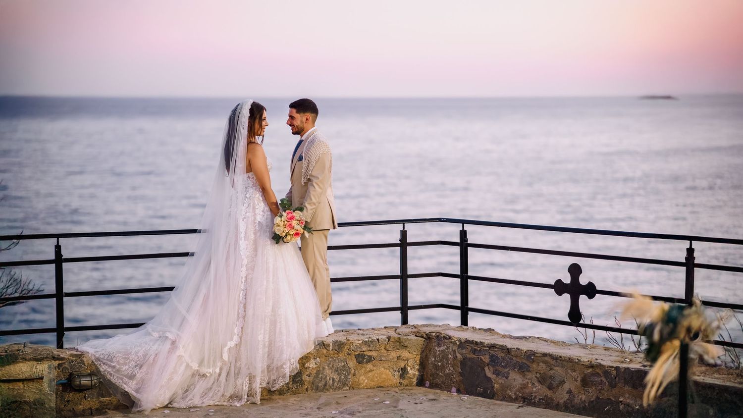Romantic coastal wedding ceremony setup with chairs and decorations at golden hour.