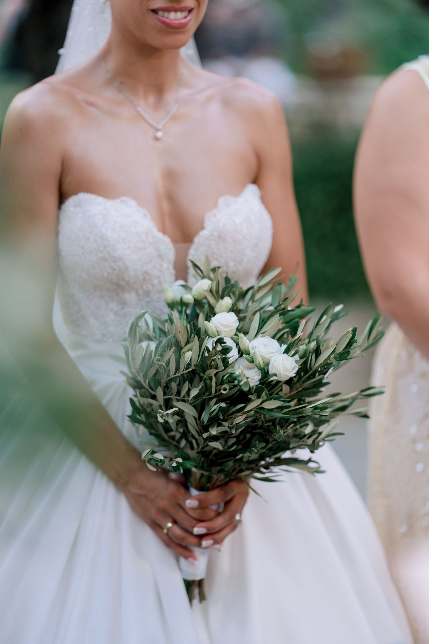 Wedding bouquets featuring olive branches and white flowers against white gowns.