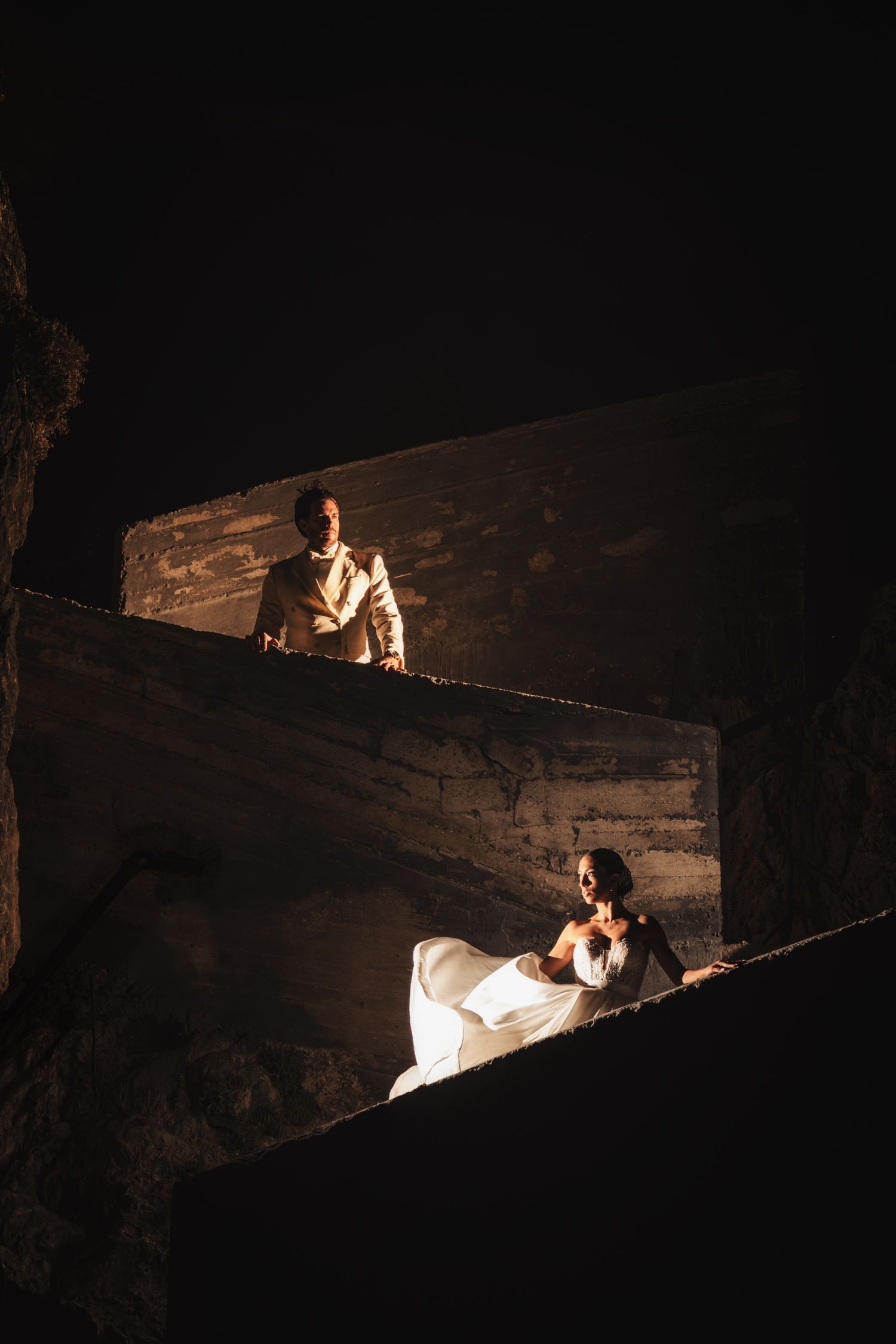 Dramatic nighttime wedding photos with couple positioned on dark stone steps.