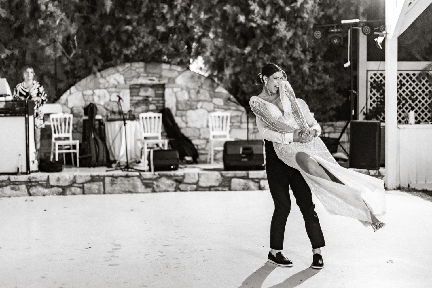 A couple performs a romantic dance dip move at an outdoor wedding reception.