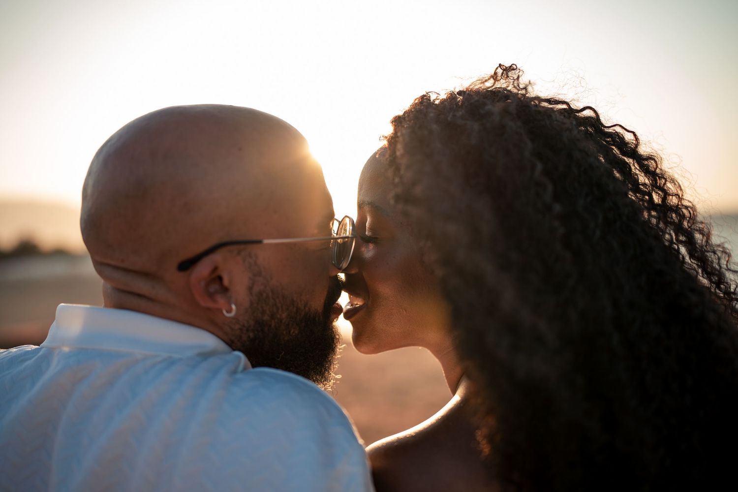 Couple sharing romantic sunset moment with ocean backdrop.