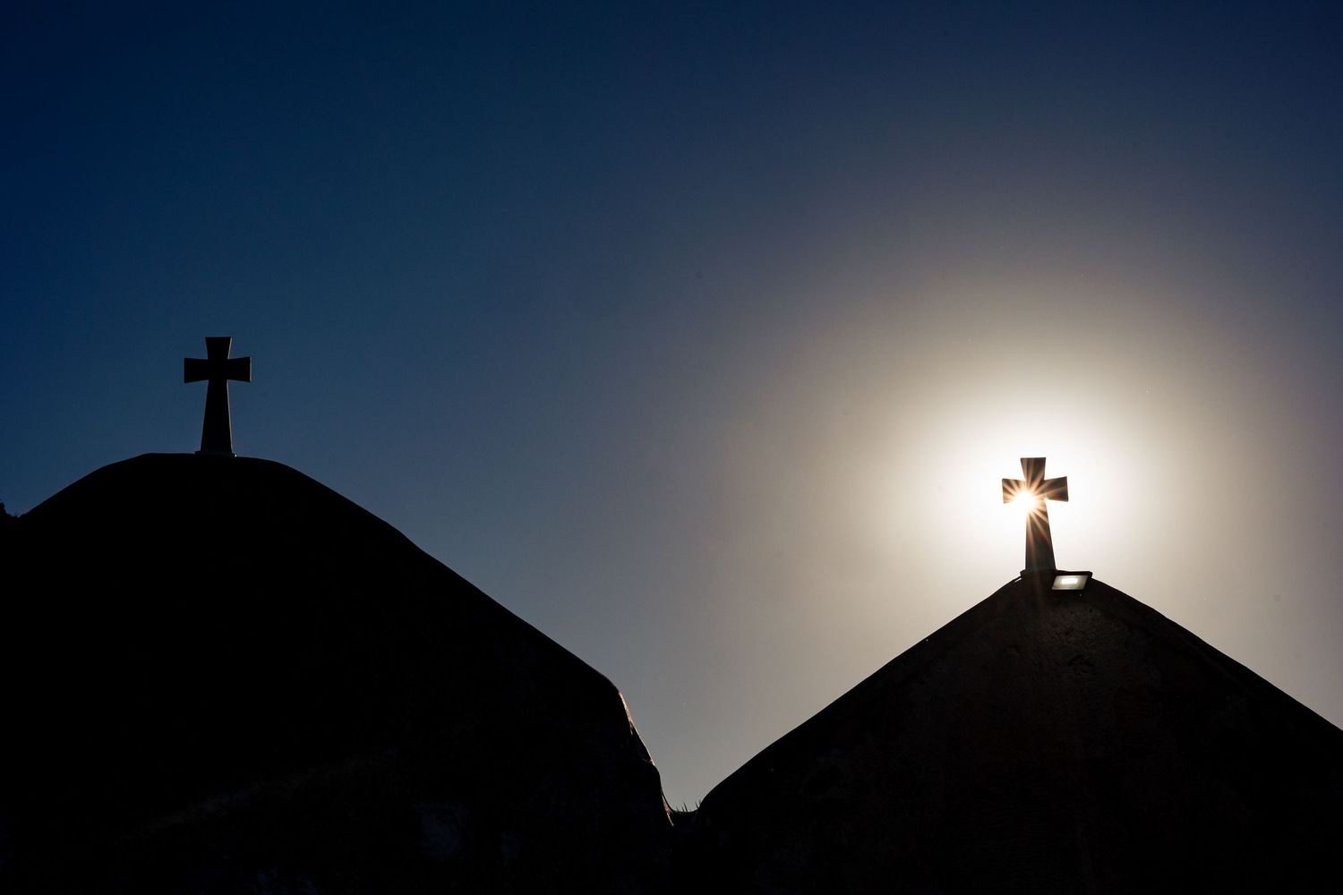 Silhouettes of church steeples against a dramatic sunset sky.