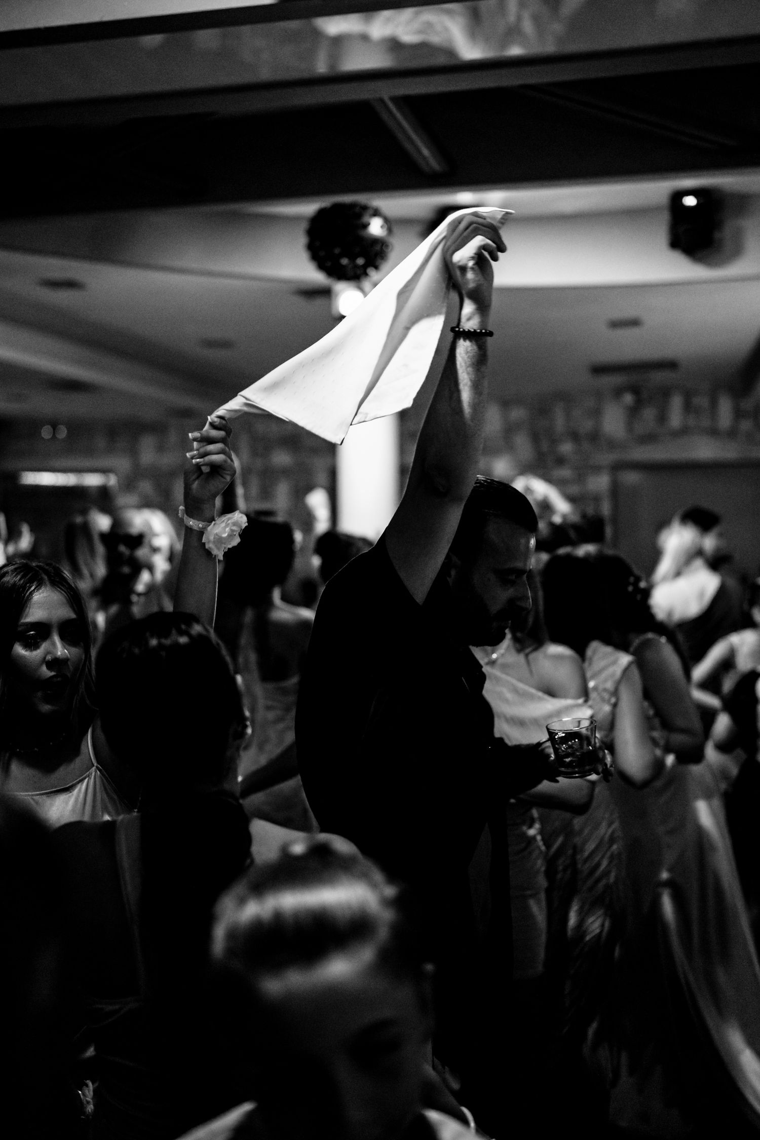 Person waving a napkin in the air during a crowded party celebration.
