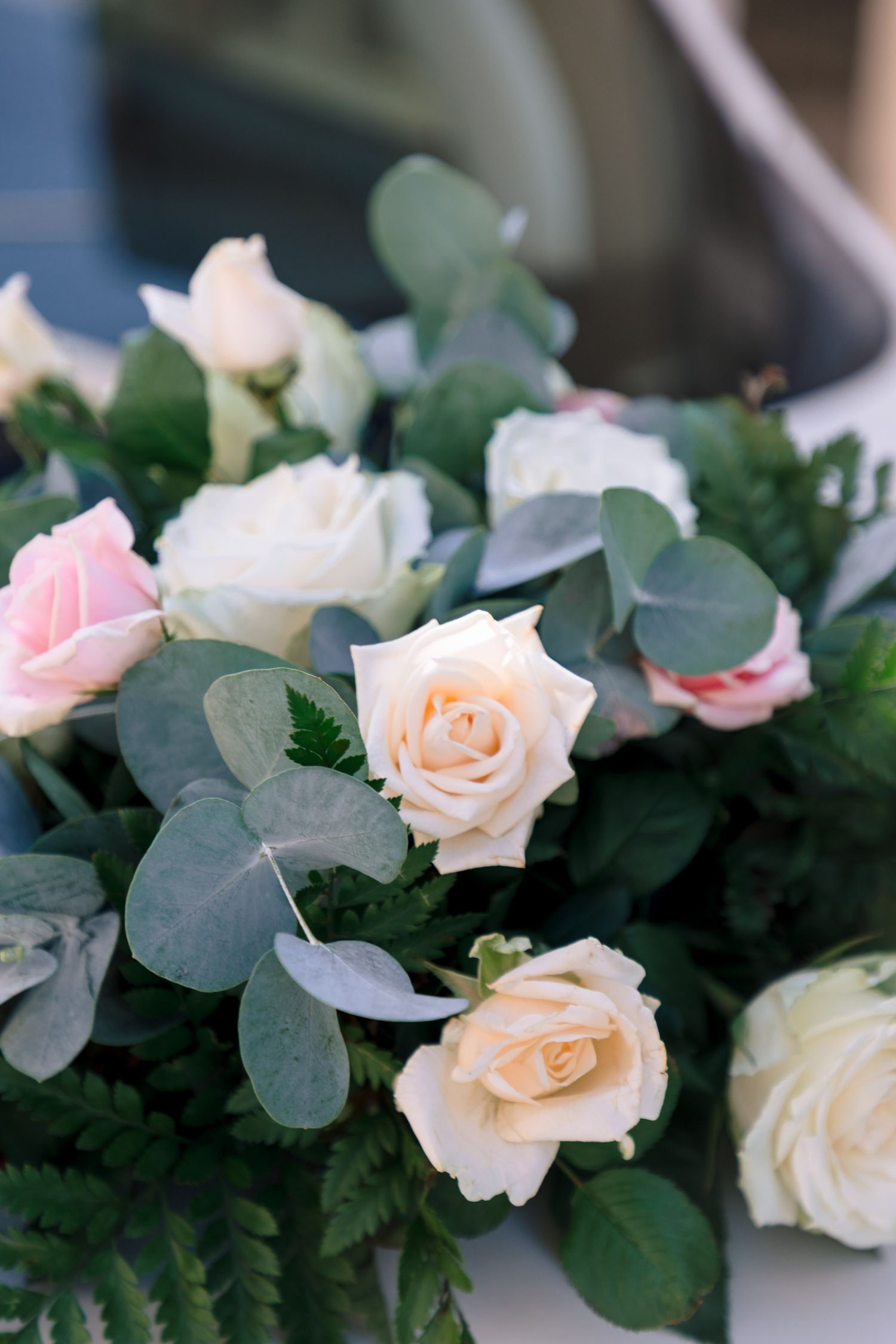 Delicate floral arrangement with pink and cream roses nestled among eucalyptus leaves.