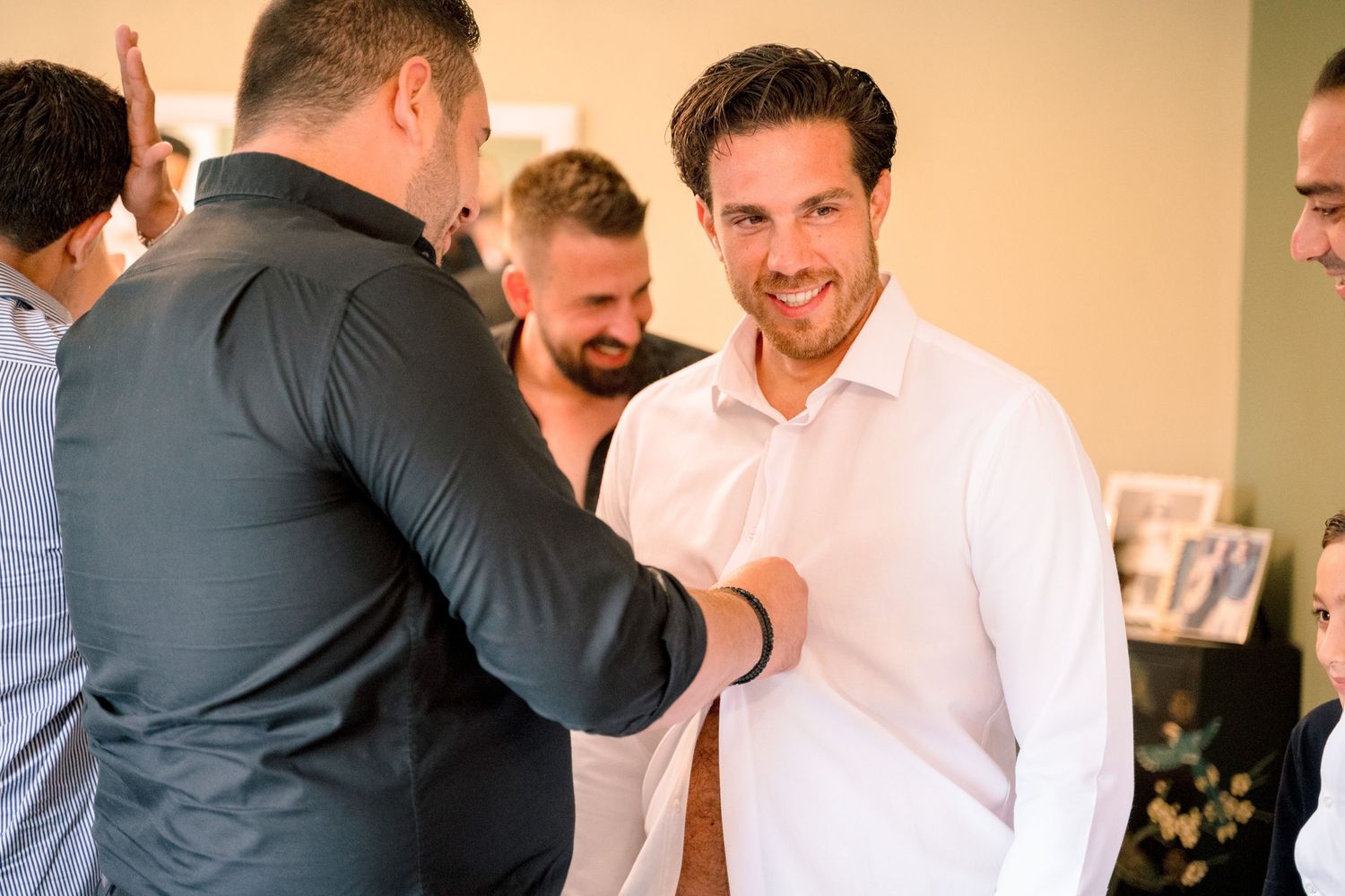 Groomsmen share laughs and hugs during pre-wedding preparations.