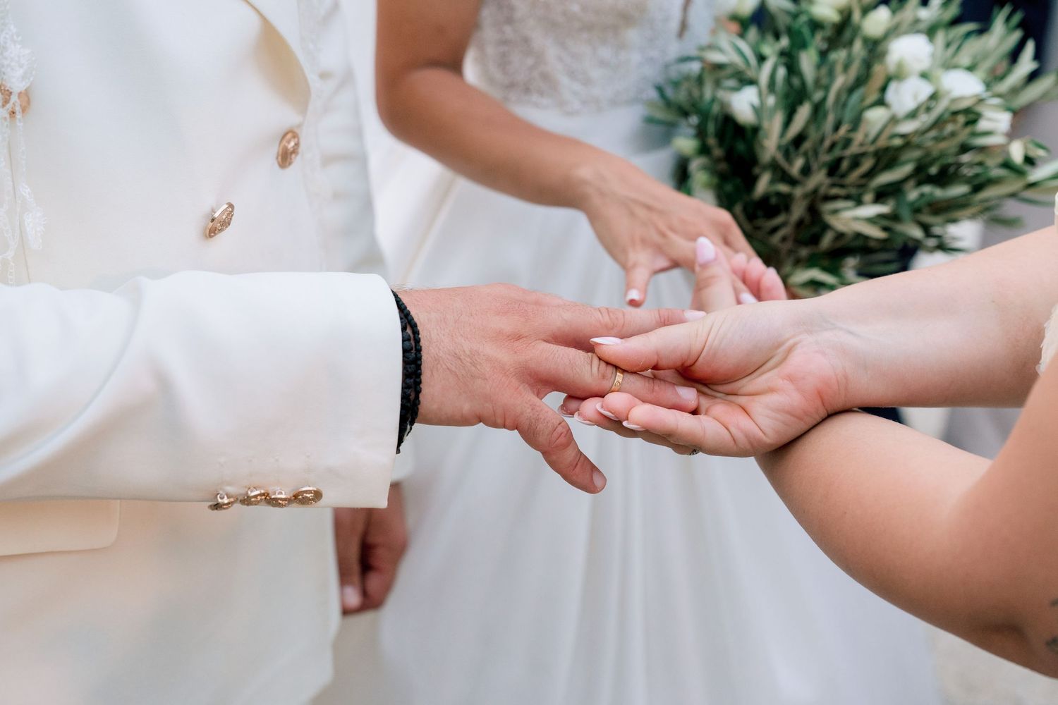 Close-up of hands exchanging rings during wedding ceremony.