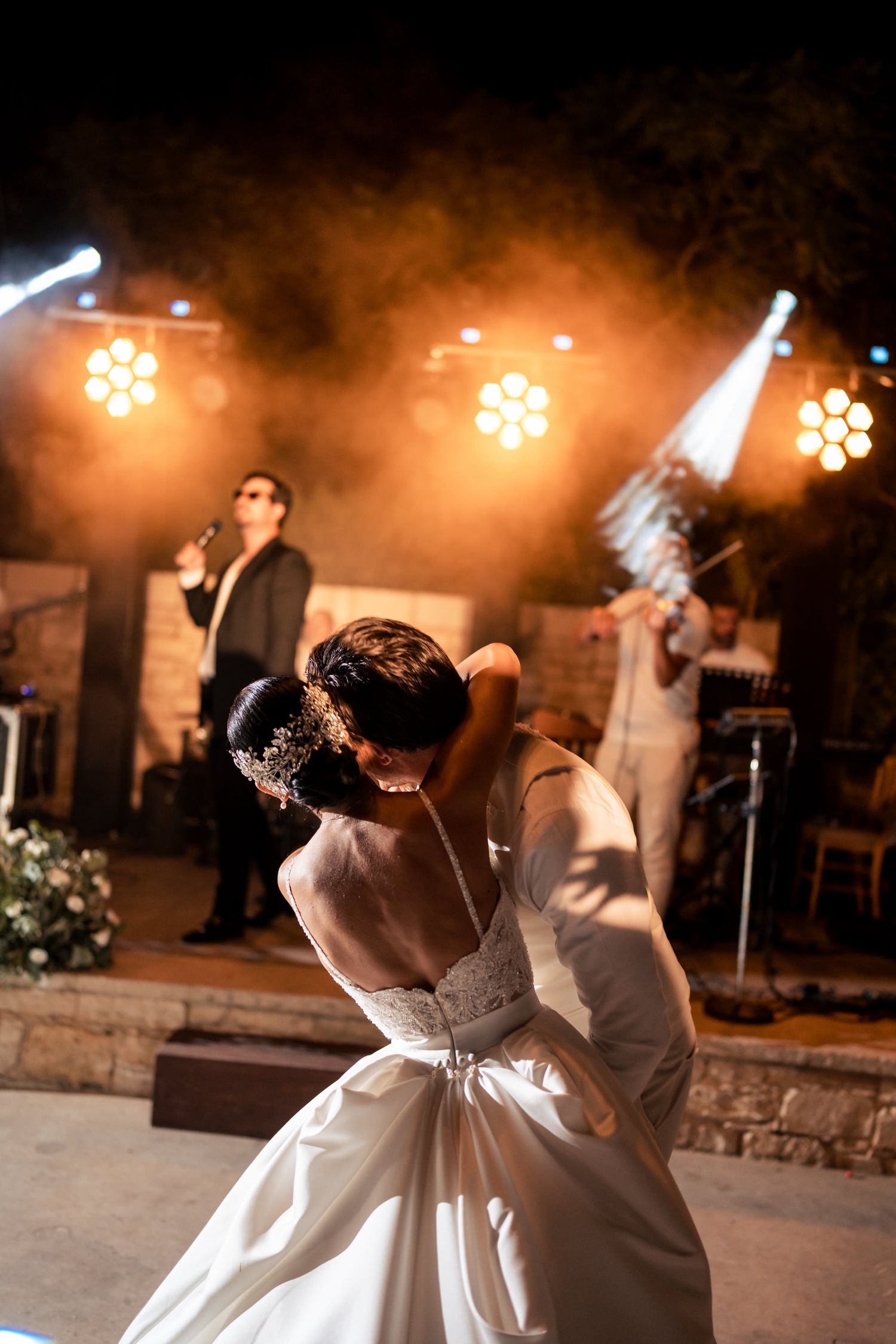 Romantic dance scene with orange stage lighting and band performing in background.