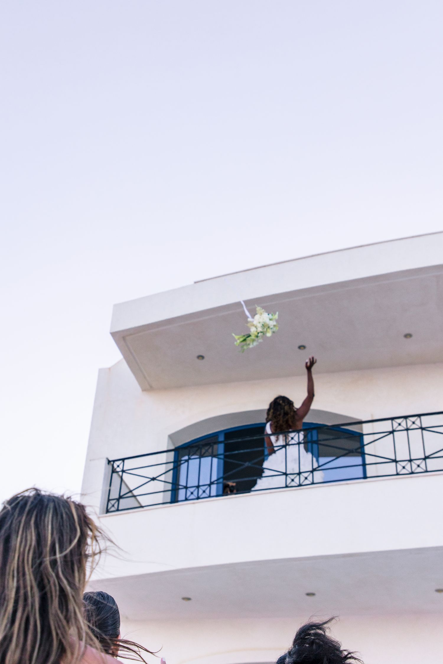 White balcony view with people celebrating against a bright sky.