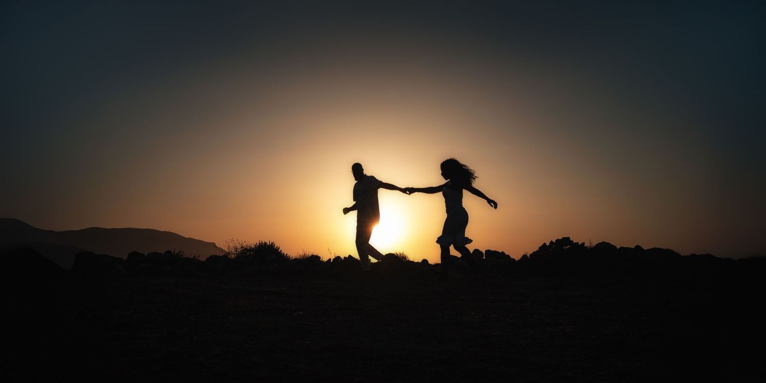Silhouettes of people walking along horizon at sunset creating dramatic scene.