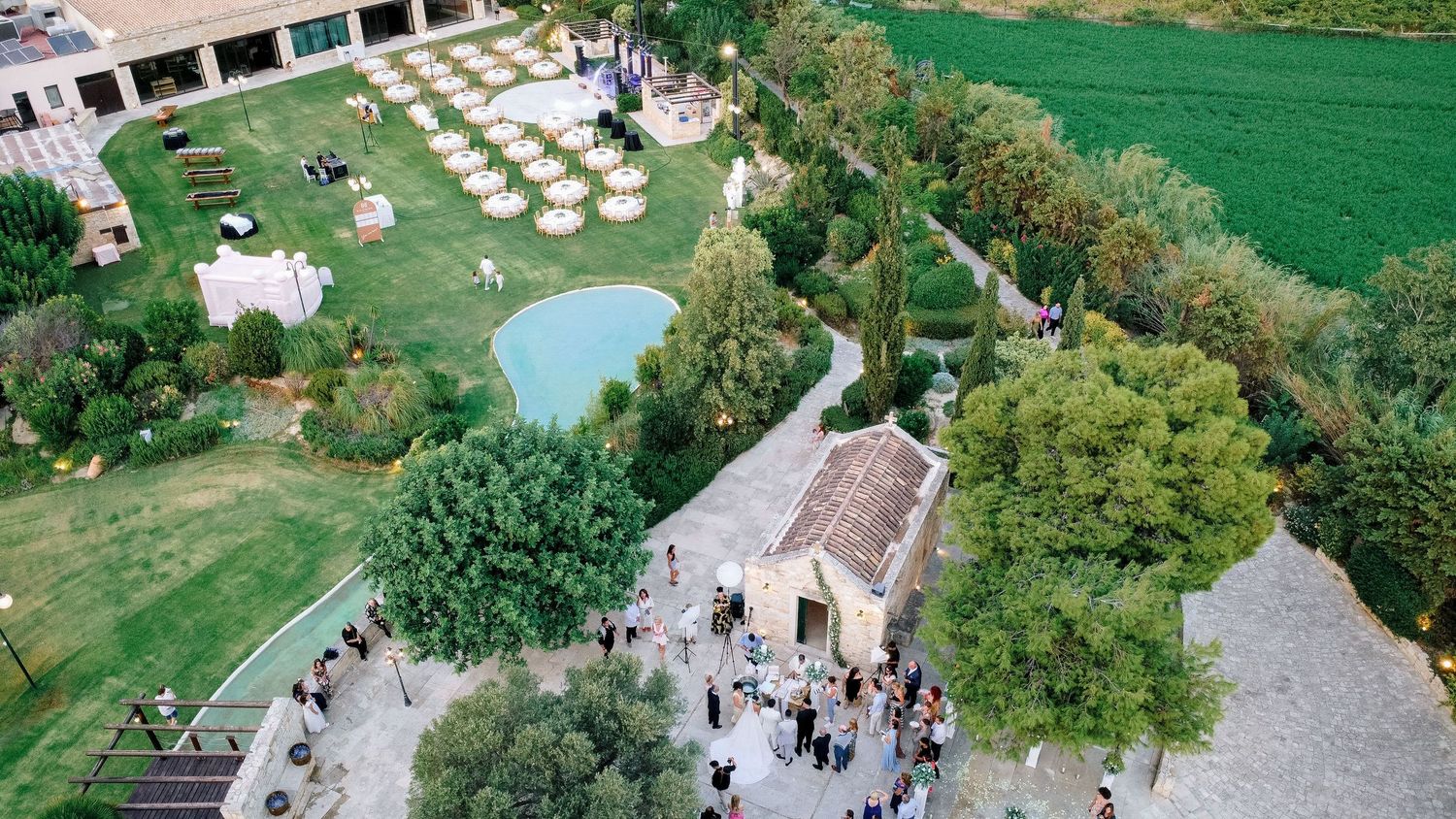 Aerial view of outdoor wedding venue with manicured gardens and guest seating.