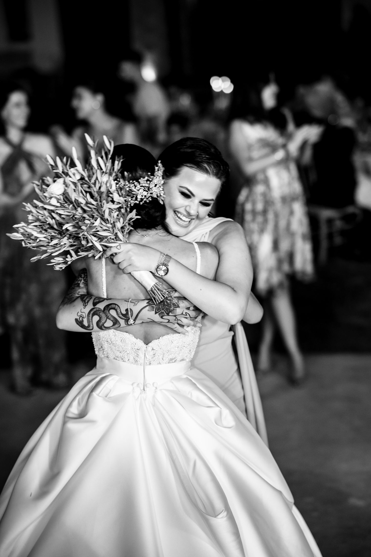 Joyful moment captured in black and white as bride hugs bouquet during reception.