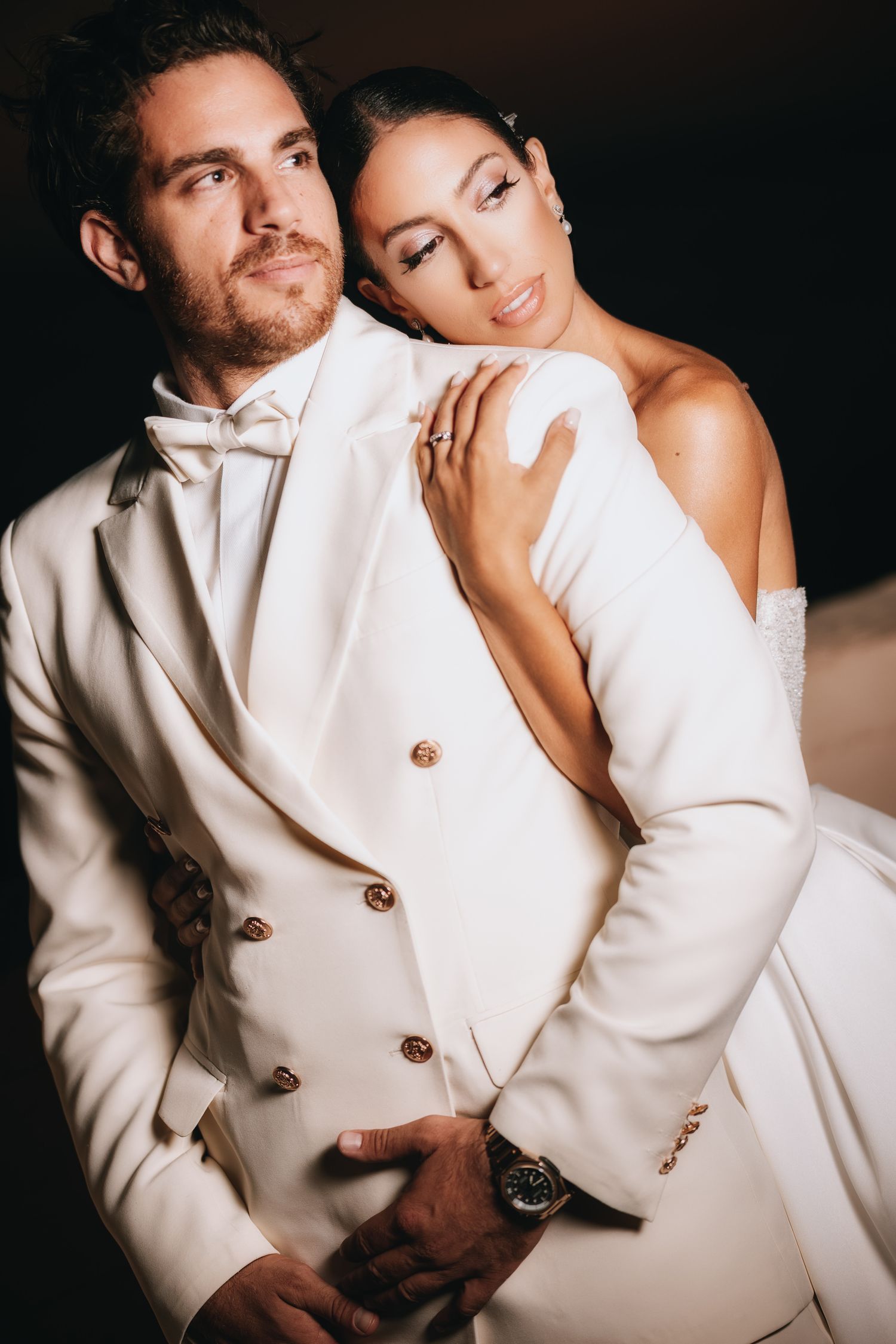 Stylish wedding couple in all-white outfits embracing in artistic portrait series.