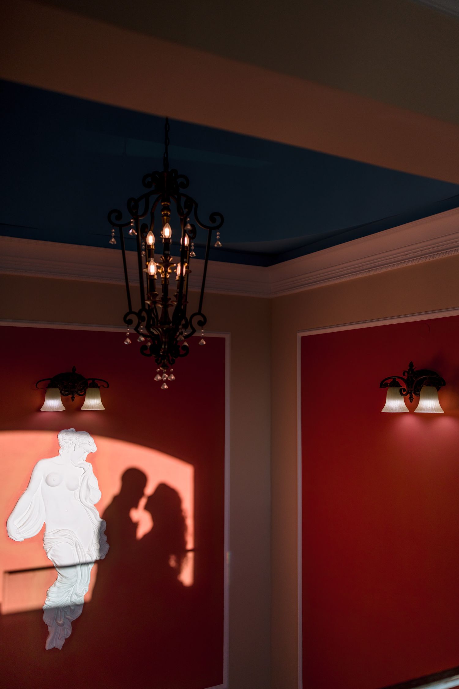Red-walled interior room with hanging light fixtures and dramatic shadow play.