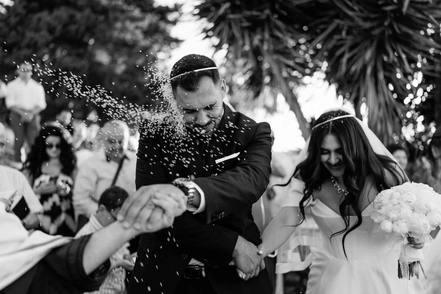 Guests shower newlyweds with confetti during a festive outdoor celebration.
