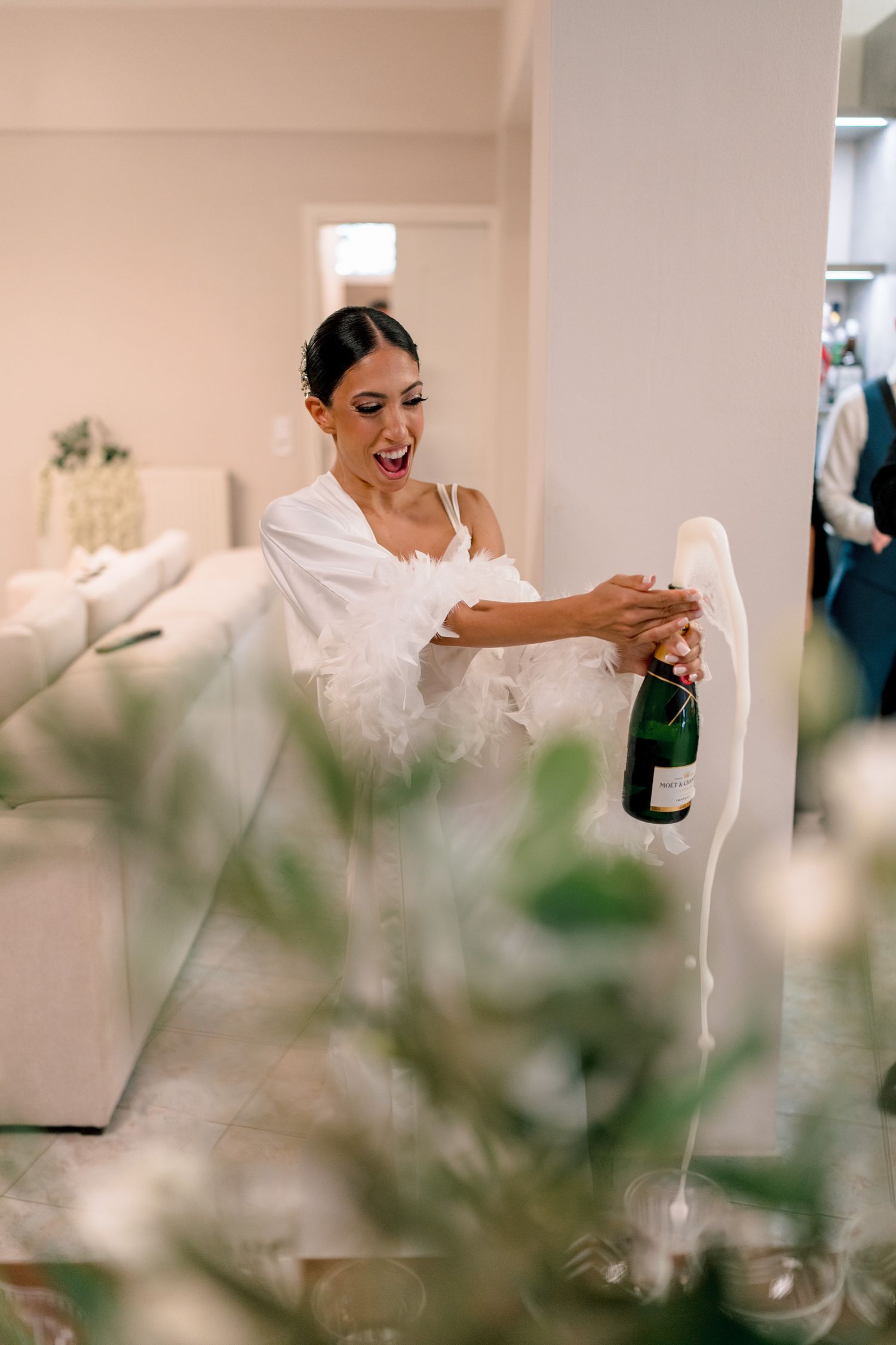 Celebratory moment with champagne and white decor during wedding preparations.