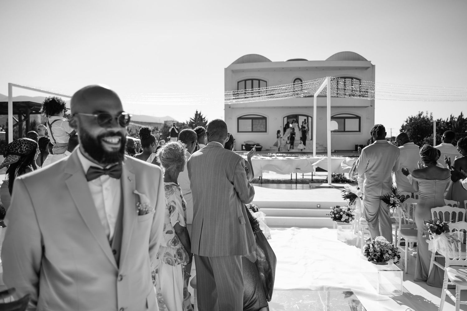 Wedding party in gray suits gathered outside on a sunny day.