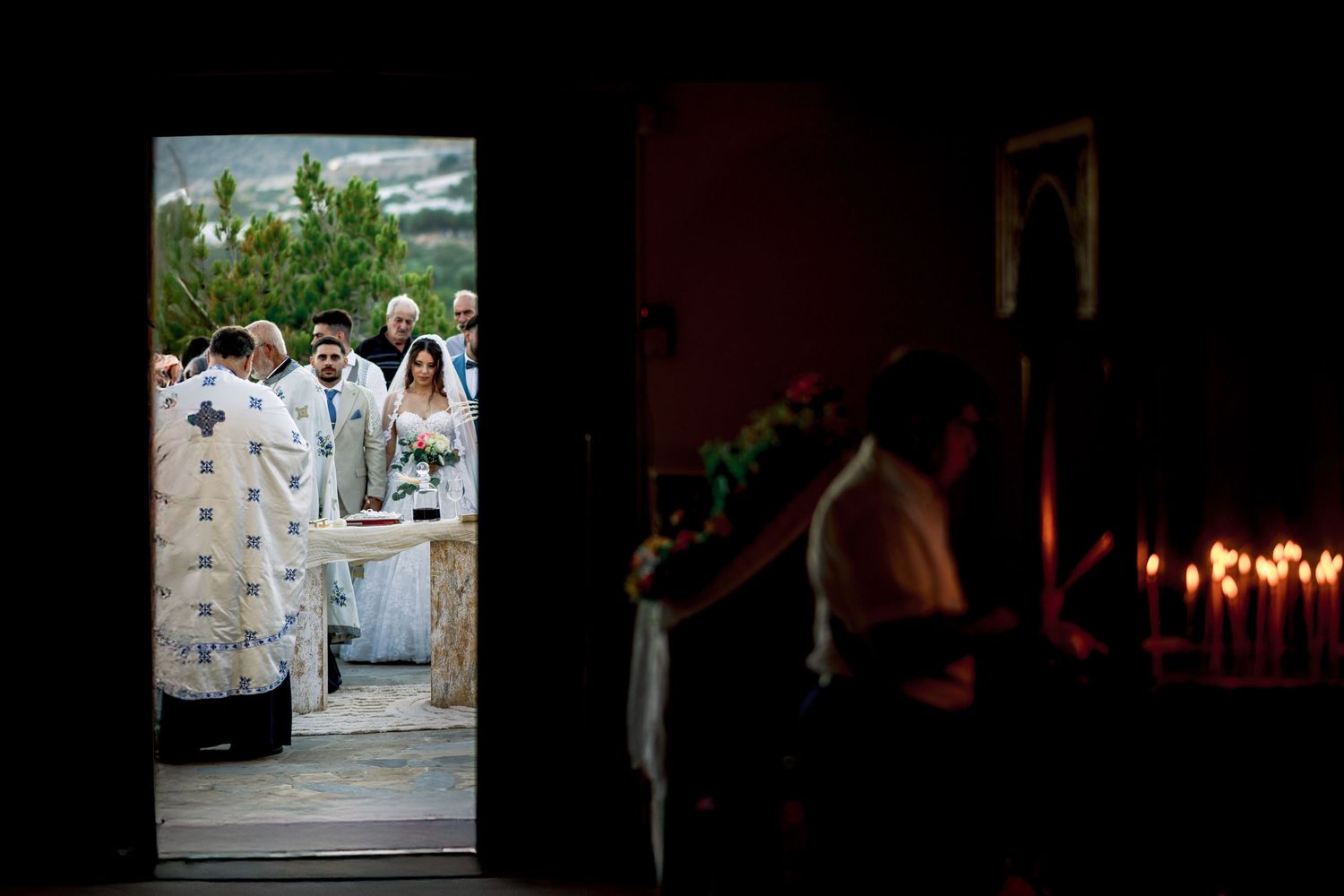 Dark reception venue with candlelit tables and dancing silhouettes creating romantic atmosphere.