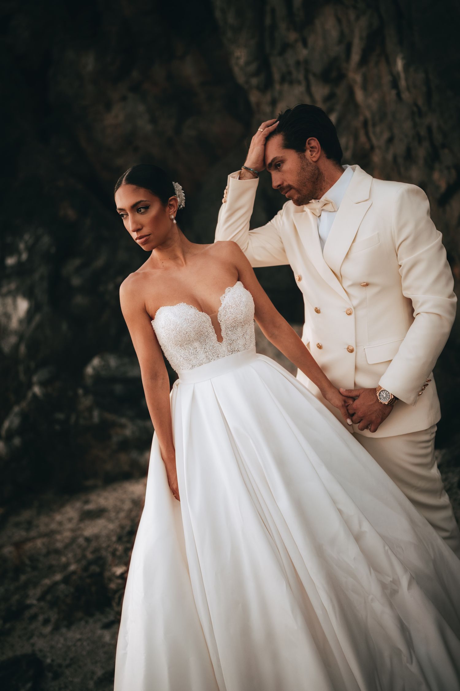 Intimate wedding portraits showing details of white dress and suit against dark background.