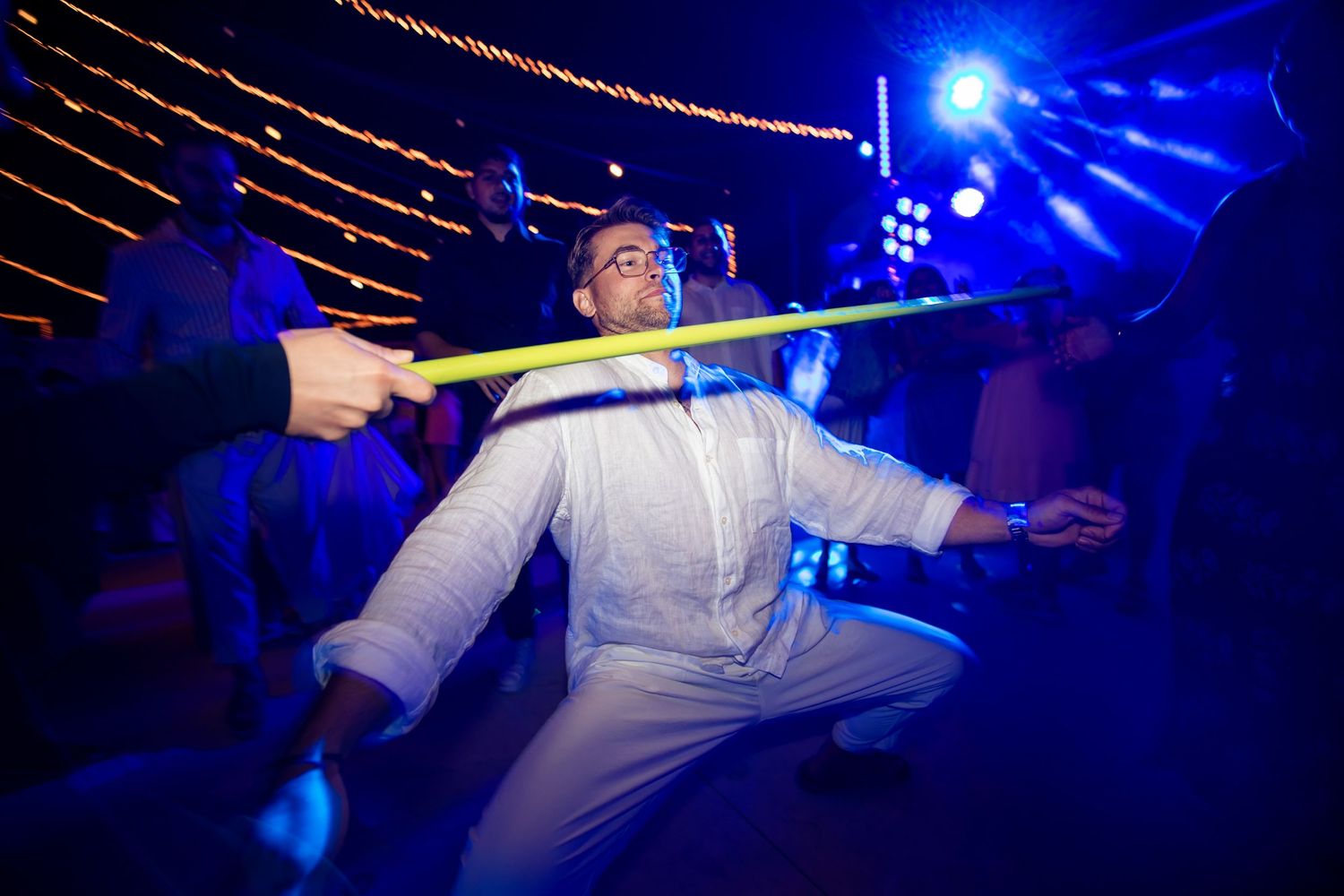 Dynamic dance moves captured under dramatic blue lighting at a nighttime celebration.