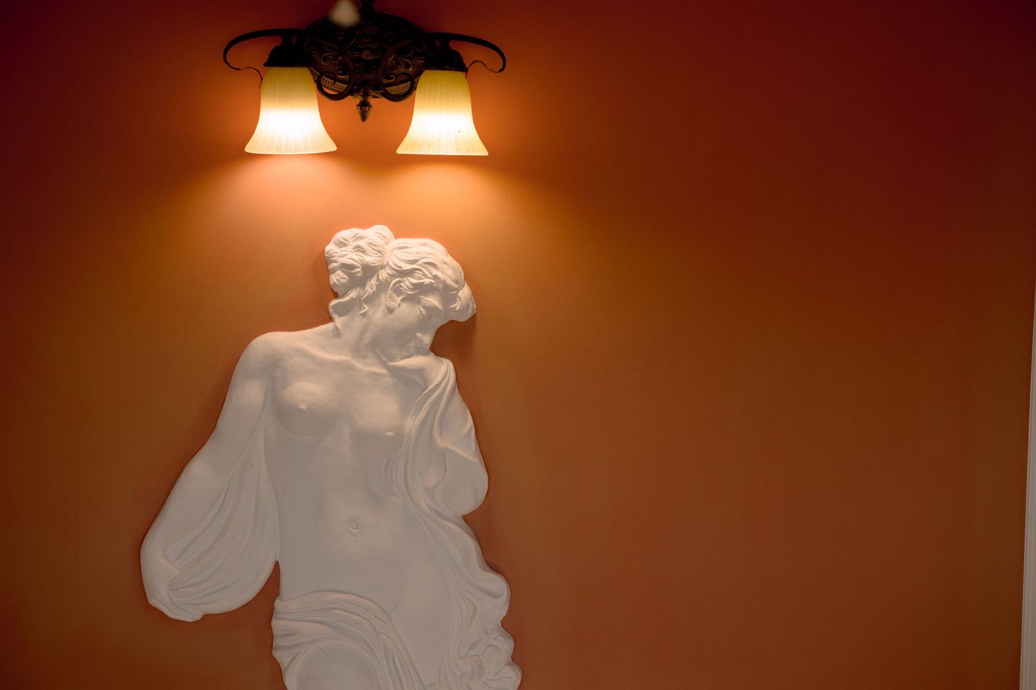 Elegant wedding dress hanging from a wall sconce with warm lighting.