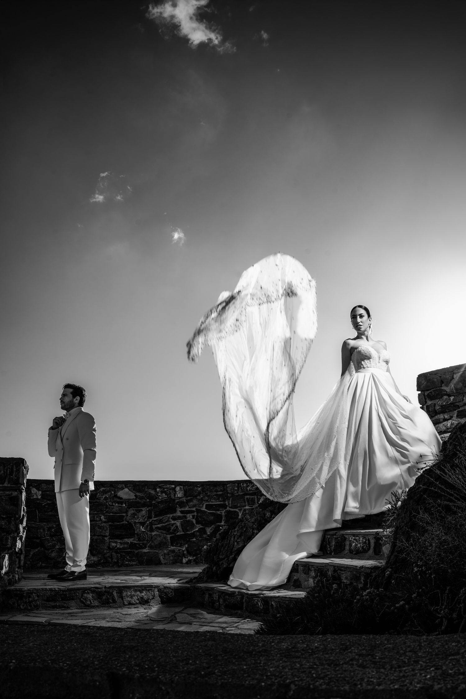 Black and white series of wedding dress movement against stone fortress walls.