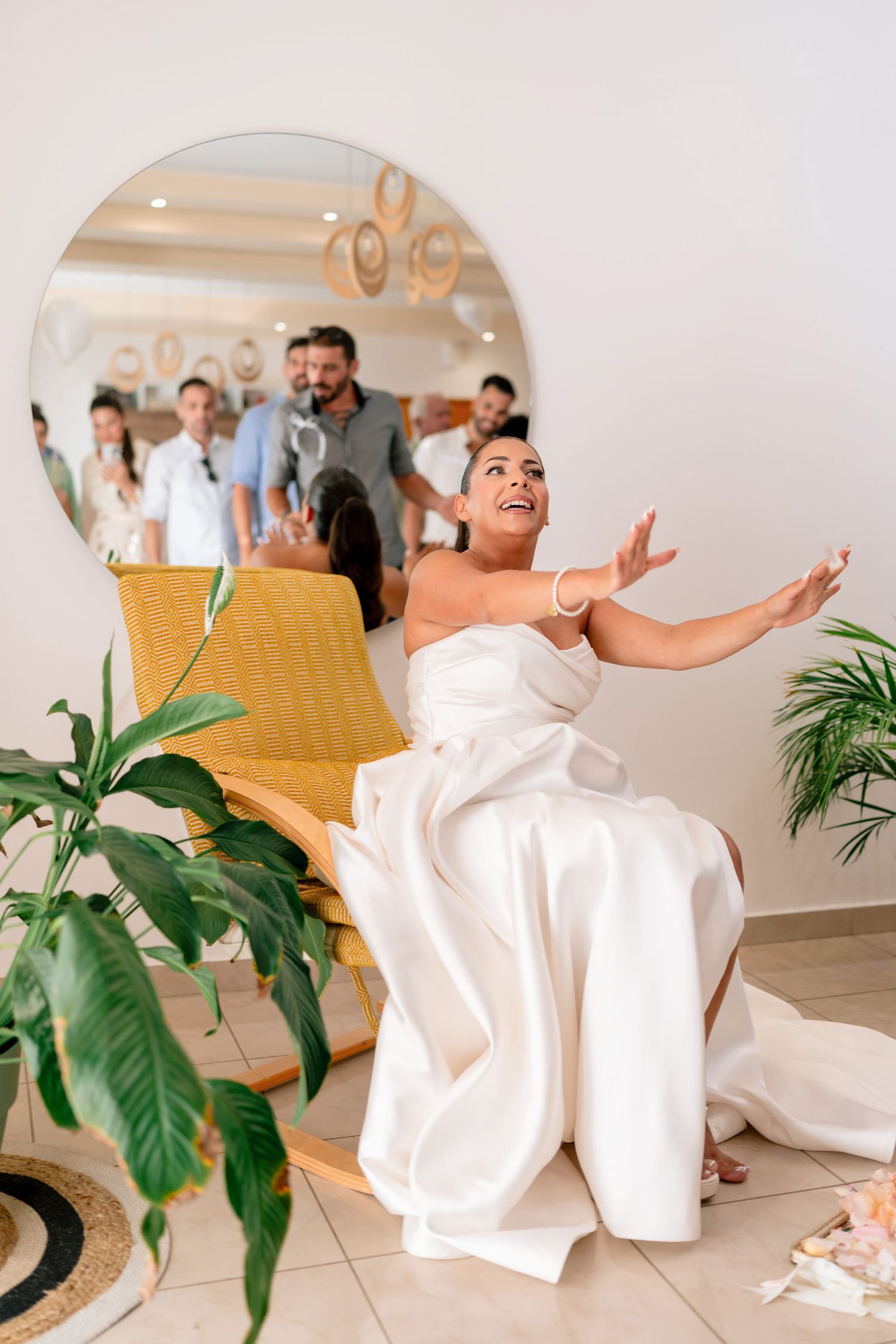Joyful wedding preparation scene with white dress and indoor decor.