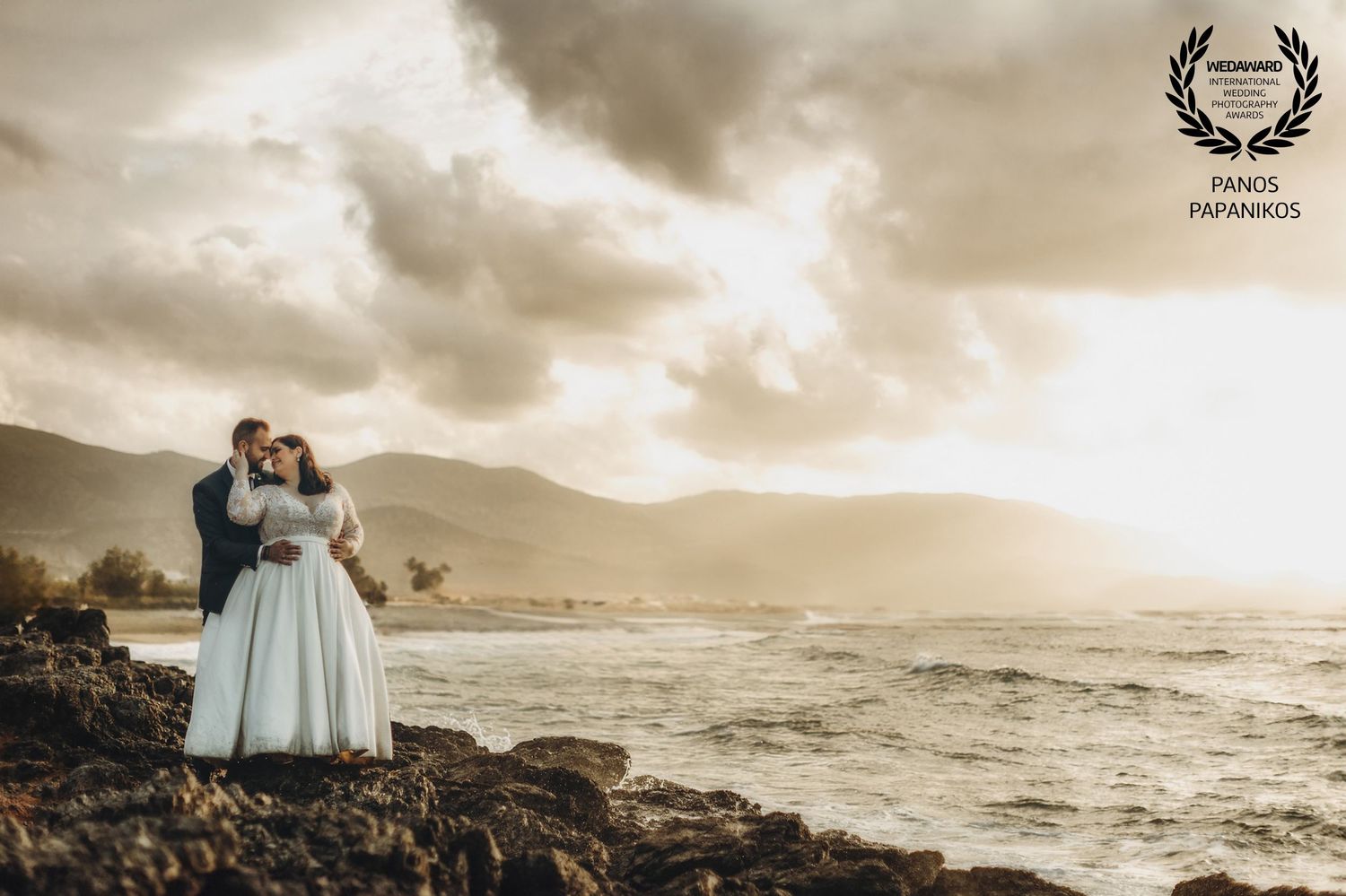 Coastal wedding scene with dramatic stormy skies and ocean waves.