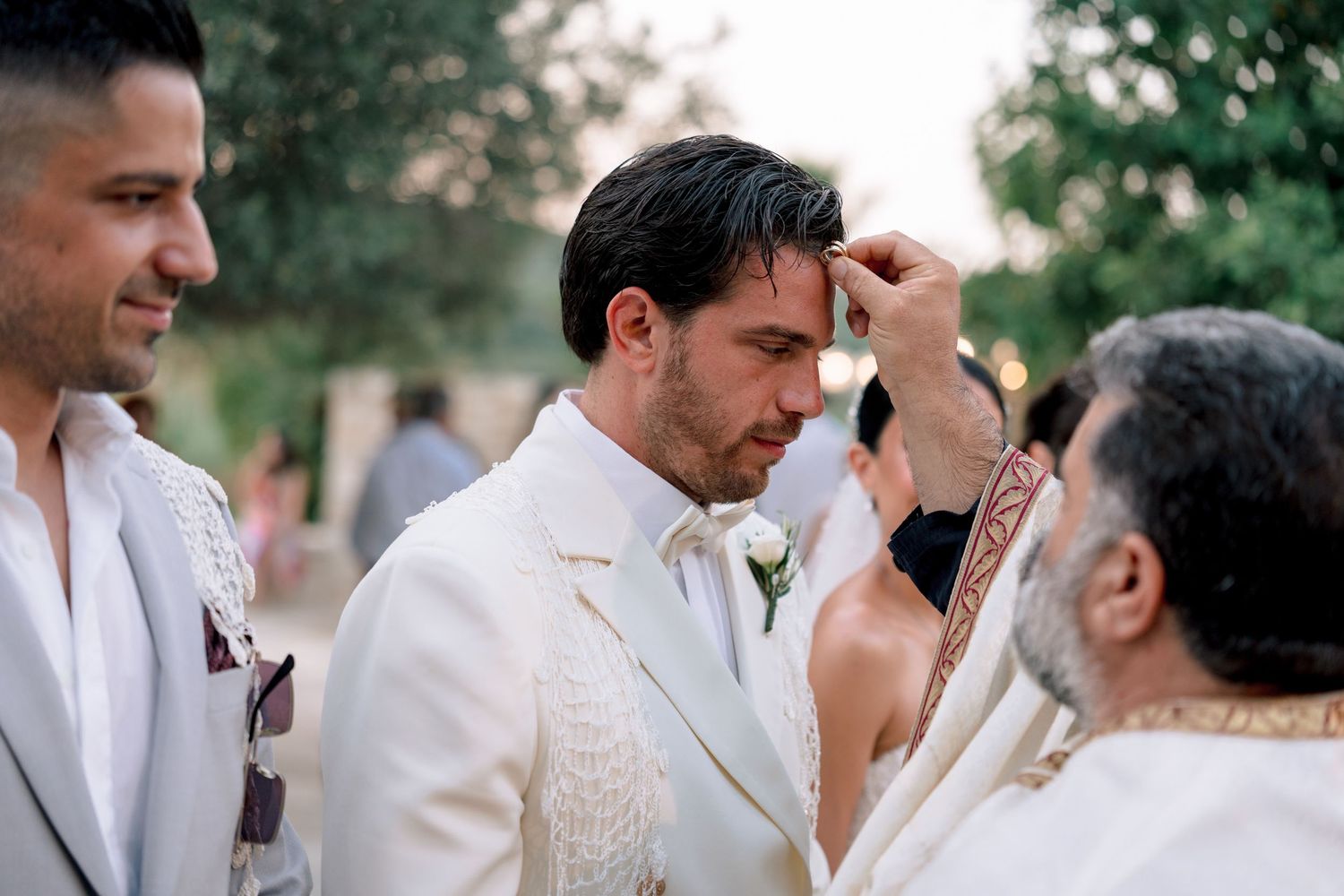 Wedding celebration gathering with guests in white attire outdoors.