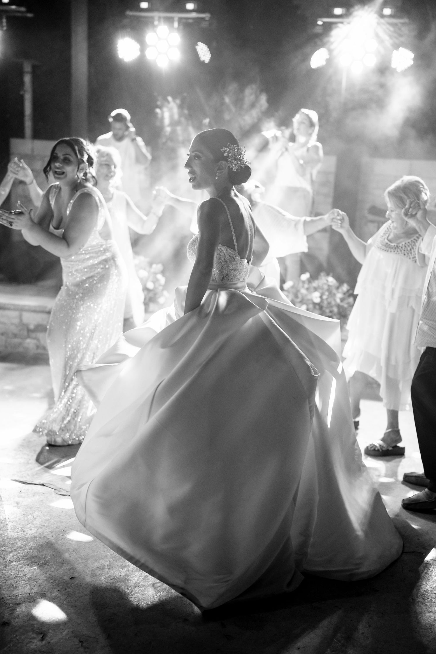 Dramatic black and white shots of wedding guests dancing with flowing dresses.
