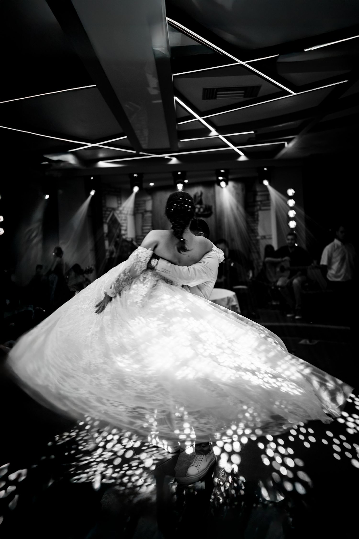 Black and white photo of a wedding dress twirling on the dance floor with dramatic lighting effects.