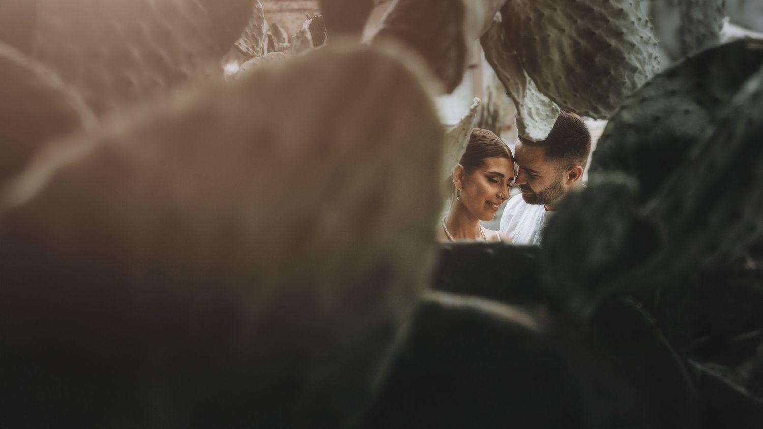 Intimate wedding moment captured through soft focus foreground elements.