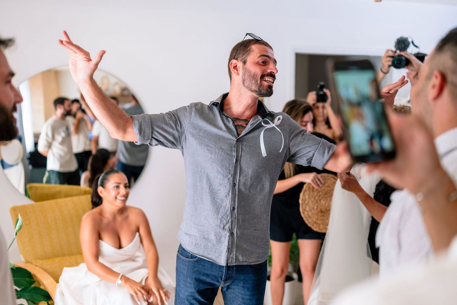 Candid reactions during wedding preparations with guests in background.